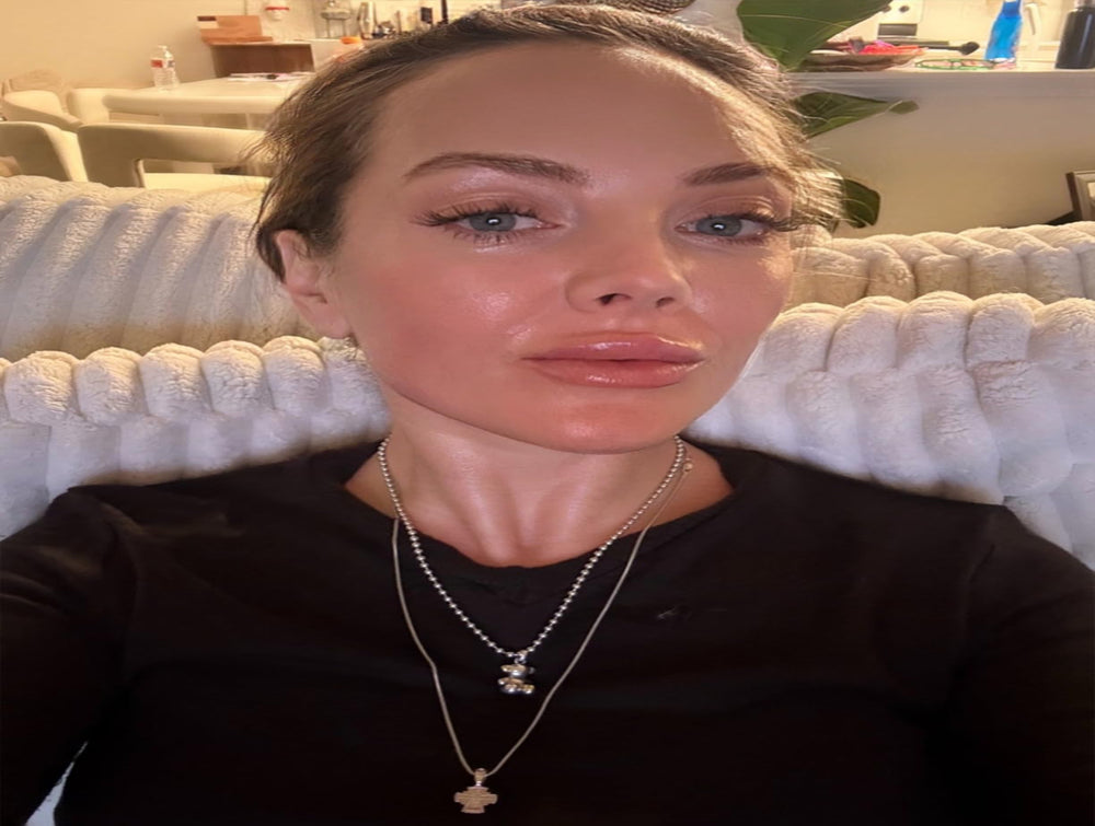 Woman wearing a black top and necklace in a room with white furniture.